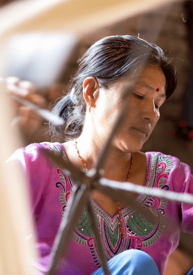Nepalesische Knüpferin vertieft in Ihre Knüpfarbeit - Geba Teppich